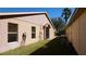 Side view of the home with a well-maintained lawn, windows, and dark metal door at 156 Grand Canal Dr, Poinciana, FL 34759
