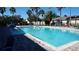A pristine community pool surrounded by lounge chairs, palm trees, and lush landscaping at 156 Grand Canal Dr, Poinciana, FL 34759