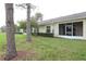 Backyard view of a home with a screened-in lanai, green grass and mature trees at 185 Club Villas Ln, Kissimmee, FL 34744