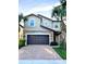Two-story house with dark brown garage door, brick driveway, and palm trees at 2112 Morocco Way, Kissimmee, FL 34747