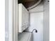 A stacked washer and dryer sit in a closet area with white shelving above at 2203 San Vittorino Cir # 107, Kissimmee, FL 34741