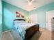 Comfortable bedroom featuring blue walls, a ceiling fan, and a queen-sized bed with stylish bedding at 3857 San Isidro Cir, St Cloud, FL 34772