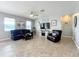 Spacious living room with a ceiling fan, multiple windows, dark leather furniture, and neutral-colored walls and flooring at 3857 San Isidro Cir, St Cloud, FL 34772