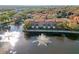 Aerial view of townhomes surrounding a pond with water features, set within a lush, tree-filled community at 6109 Metrowest Blvd # 105, Orlando, FL 32835