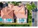 Aerial view of terra cotta rooftops showcasing two screened pools in a community with verdant landscaping at 802 Brunello Dr, Davenport, FL 33897
