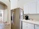 Kitchen featuring stainless steel refrigerator and white cabinets, blending functionality and contemporary style at 802 Brunello Dr, Davenport, FL 33897