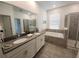 Bathroom featuring double sink vanity, soaking tub, and a walk-in shower with gray tile surround at 8885 Cabot Cliffs Dr # 103, Davenport, FL 33896