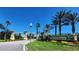 ChampionsGate community entrance featuring beautifully manicured landscaping, signage, and palm trees against a blue sky at 8885 Cabot Cliffs Dr # 103, Davenport, FL 33896