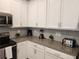 Modern kitchen with white cabinets, gray countertops, and stainless steel appliances at 8885 Cabot Cliffs Dr # 103, Davenport, FL 33896