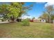 A large backyard with lush green grass, a large tree and multiple storage sheds at 900 Delaware Ave, St Cloud, FL 34769