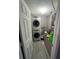 Compact laundry room with stacked washer and dryer unit, storage shelves, and neutral paint at 920 Gillingham Ct, Kissimmee, FL 34758