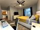 Neutral bedroom showcasing hardwood floors, TV, fan, and yellow bedspread at 11446 Jasper Kay Ter # 106, Windermere, FL 34786