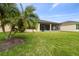 Manicured backyard with palm trees, a screened lanai, and lush green grass at 1398 Del Mar Dr, Kissimmee, FL 34759