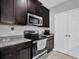 Modern kitchen with granite countertops, dark wood cabinets and stainless steel appliances at 1669 Swan Swim Dr, Davenport, FL 33837