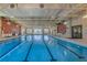 Bright indoor swimming pool featuring multiple lanes and large windows for natural light and a door to the outside at 246 Tomelloso Way, Davenport, FL 33837