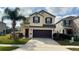 Two-story home featuring a two-car garage, manicured lawn and tropical palm tree at 3199 Turret Dr, Kissimmee, FL 34743