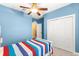 Cheerful bedroom with blue walls, white closet doors and a striped bedspread, plus entry to the hallway at 3329 Schoolhouse Rd, Harmony, FL 34773
