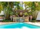 Close up of the lovely water feature including potted plants, a stone wall and flowing water into the pool at 3329 Schoolhouse Rd, Harmony, FL 34773