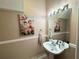 Elegant half bath with pedestal sink, decorative mirror, and floral artwork at 3491 Allegra Cir, St Cloud, FL 34772