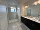 Bright bathroom featuring dual sink vanity, framed mirror, contemporary lighting, and a walk-in shower at 4740 Tribute Trl, Kissimmee, FL 34746