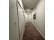 A well-lit hallway with neutral carpet and white walls, leading to various rooms in the home at 4740 Tribute Trl, Kissimmee, FL 34746