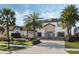 Charming two-story home with a stone facade, mature palm trees, and a paver driveway at 4959 Tennessee Lake Dr, Auburndale, FL 33823