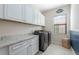 Laundry room with white cabinets, granite counters, modern washer and dryer, and tile floors at 4959 Tennessee Lake Dr, Auburndale, FL 33823