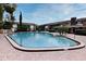 Community pool surrounded by lush landscaping near brick buildings under a sunny sky at 777 W Lancaster Rd # A-13, Orlando, FL 32809