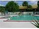 Community pool with a seating area under green umbrellas enclosed by a fence at 7900 S Orange Blossom Trl # 1039, Orlando, FL 32809