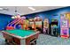 Fun-filled game room with pool table, arcade games, and bright blue accent wall at 8961 California Palm Rd, Kissimmee, FL 34747