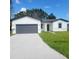 Charming single-story home with a well-manicured lawn, gray accents, and a driveway leading to an attached garage at 915 Alsace Dr, Kissimmee, FL 34759