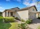 Charming single-story home with a well-manicured lawn and a brick paved driveway, set against a bright blue sky at 1036 Salamanca Pl, Davenport, FL 33837