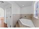 Bathroom featuring a soaking tub with tile surround, a stained glass window, and an arched doorway at 1067 Ronlin St, Haines City, FL 33844