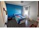 bedroom with bright blue accent wall and wood-look flooring and organized toys at 1292 Cascades Ave, Davenport, FL 33837