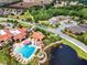 Community pool showcasing sun loungers and shade canopies, set amidst verdant greenery and a lake at 142 Magellan Ct, Davenport, FL 33837