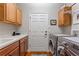 Well-lit laundry room features wood cabinets, washer, dryer, and a convenient utility sink at 142 Magellan Ct, Davenport, FL 33837