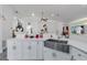 Kitchen featuring a large stainless steel farmhouse sink, white cabinets, and a view into the living area at 1520 Oak Hill Trl, Kissimmee, FL 34747