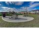 Community picnic area with tables, landscaping and playground in the background at 1567 Dawnview Way, Kissimmee, FL 34744