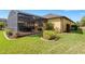 Exterior shot of the backyard showcasing lush landscaping, screened patio, and well-maintained lawn at 208 Almeria Way, Davenport, FL 33837