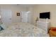 Comfortable bedroom featuring a tropical-patterned bedspread, and a television with a white dresser at 208 Almeria Way, Davenport, FL 33837