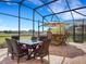 Spacious screened patio with outdoor dining set, kitchen/bar island with grill, and comfortable seating at 208 Almeria Way, Davenport, FL 33837