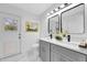 Bright bathroom featuring a double vanity with gray cabinets, sleek fixtures, and white marble floors at 2488 Pine Chase Cir, St Cloud, FL 34769