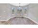 Bright dining area featuring wood-look floors, three windows, and a modern chandelier at 2488 Pine Chase Cir, St Cloud, FL 34769