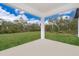 View of a large grassy backyard bordered by mature trees, seen from a covered concrete patio at 2609 Sw 154Th Lane, Ocala, FL 34473