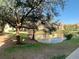 Scenic view of a pond reflecting nearby apartments, framed by lush trees and greenery, and a sunny sky at 3004 Parkway Blvd # 202, Kissimmee, FL 34747