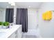 Bright bathroom featuring a tub with shower, gray shower curtain, a double vanity, and yellow towels at 3120 Paradox Cir # 204, Kissimmee, FL 34746