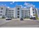 View of a modern condo building with well-maintained landscaping and ample parking under a sunny sky at 3180 Paradoux Circle # 205, Kissimmee, FL 34746