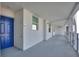 A bright, airy hallway leading to a unit's blue front door with contemporary white walls and metal railings at 3180 Paradoux Circle # 205, Kissimmee, FL 34746