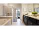 Bright bathroom featuring dual vanities with granite countertops, a soaking tub, and a walk-in shower with seamless glass door at 3348 Lilac Way, Davenport, FL 33897