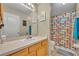 Colorful bathroom featuring a single sink vanity and a shower with a bright, patterned curtain at 3642 Doe Run Dr, St Cloud, FL 34772